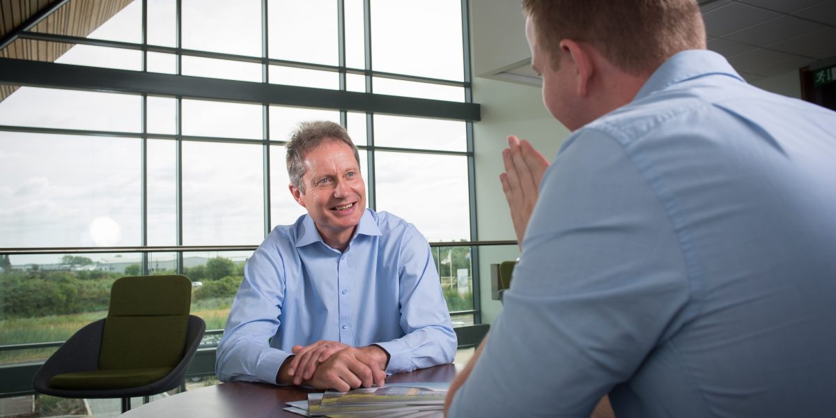 Two men talking across a desk