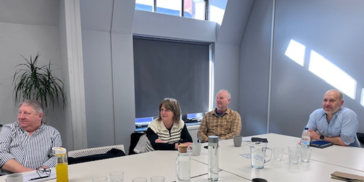Business owners sit around a table in workshop environment