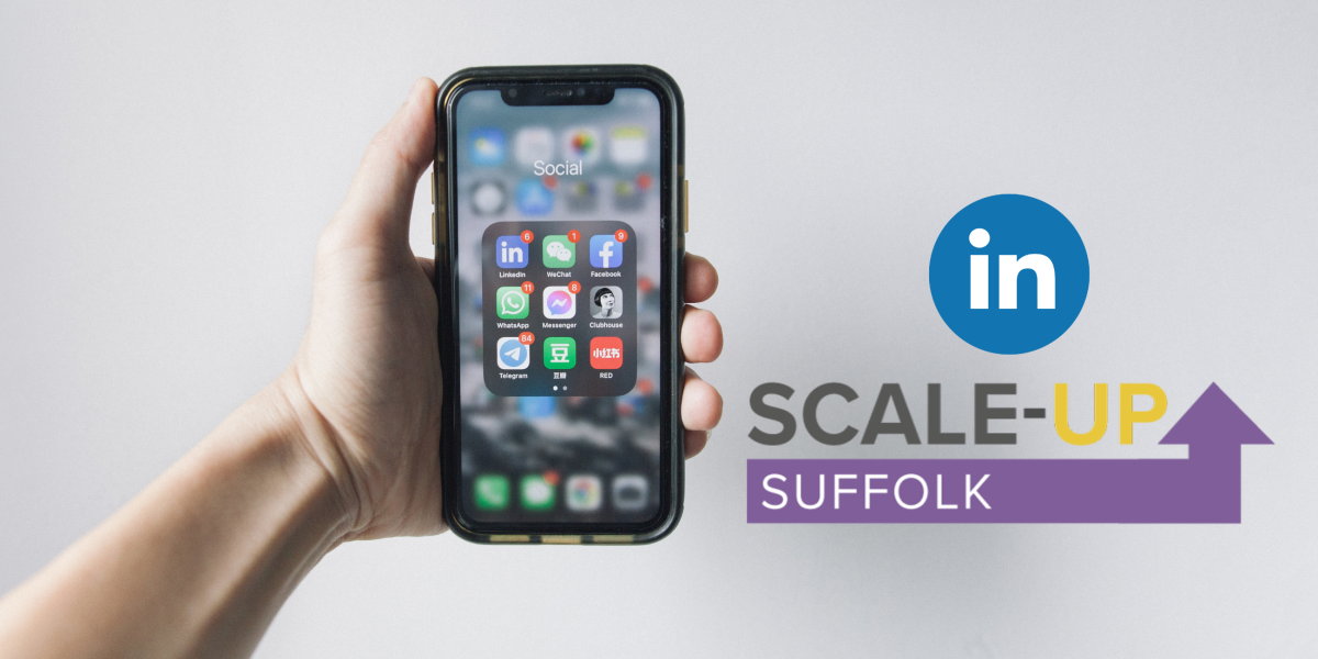 Hand holding a smartphone with social media icons on screen and banner that says scale up Suffolk