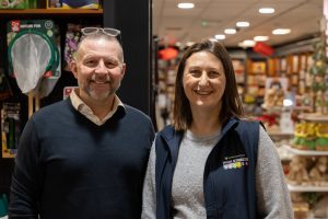 Two people s,iling at store in Norwich and High Streets Matter logo on gilet